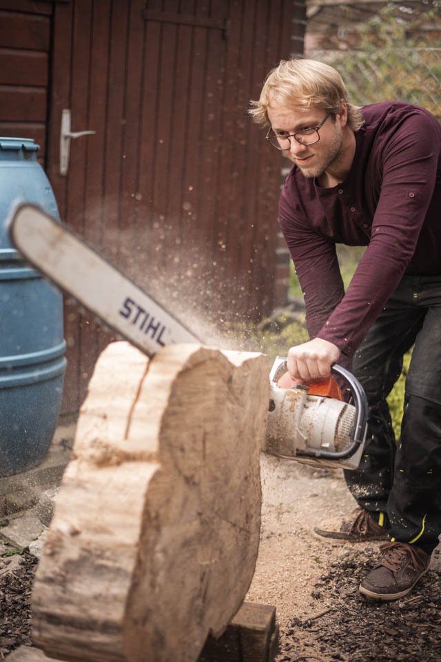 Arbeiter schneidet einen Holztisch-Rohling mit der Motorsäge